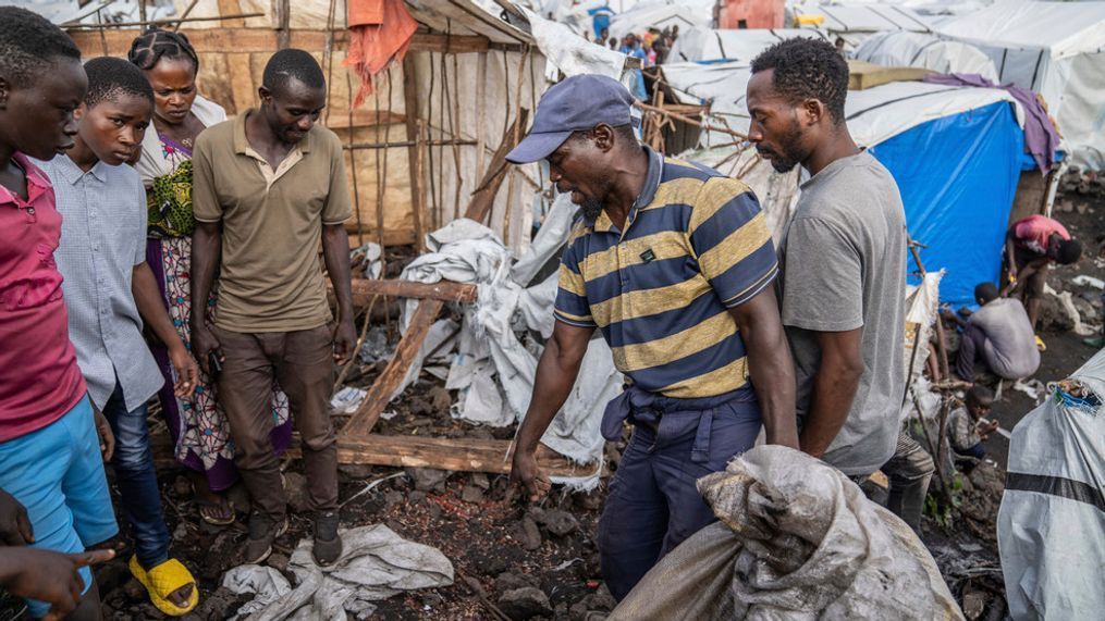 People gather at the side of an explosion in a refugee camp on the outskirts of Goma, Democratic Republic of the Congo, Friday, May, 3, 2024. The Congolese army says a bomb at a refugee camp in eastern Congo has killed at least 5 people, including children. An army spokesman blamed the attack at the Mugunga refugee camp in North Kivu